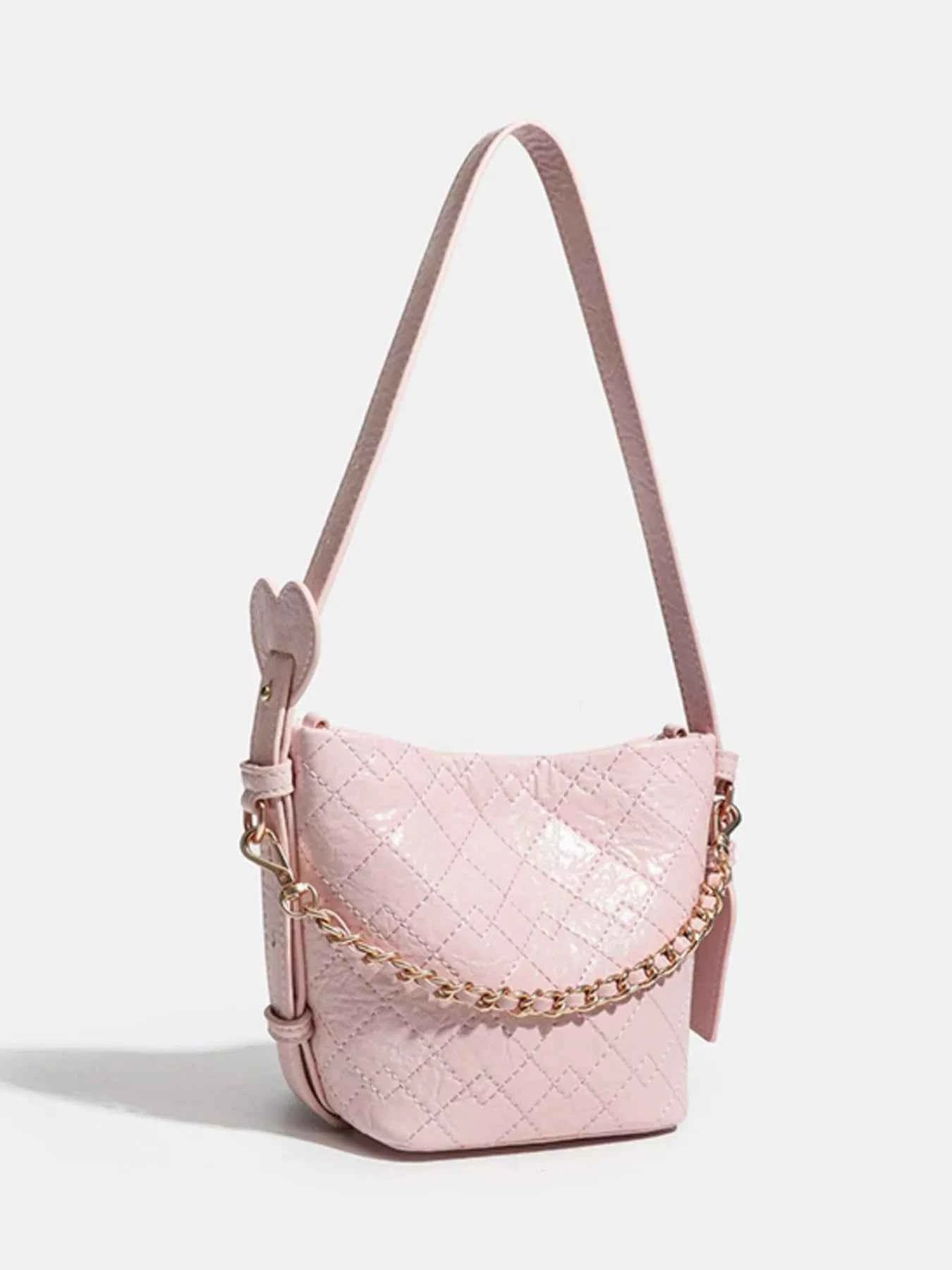 Pink quilted crossbody bag with gold chain strap and heart detail, stylish fashion accessory
