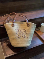 Woven straw tote bag with monogram embroidery and leather handles, stylish summer accessory