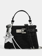 Black textured handbag with silver star charm, top handle, and chain strap, fashion accessory