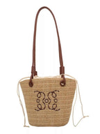 Straw tote bag with brown leather handles and embroidered floral design, perfect for summer fashion.