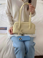 Cream bowler bag with star charm, held by woman in cozy outfit, perfect for trendy fashion accessories.