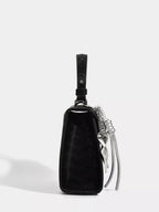 Black textured mini handbag with silver chain strap and tassel detail, stylish fashion accessory