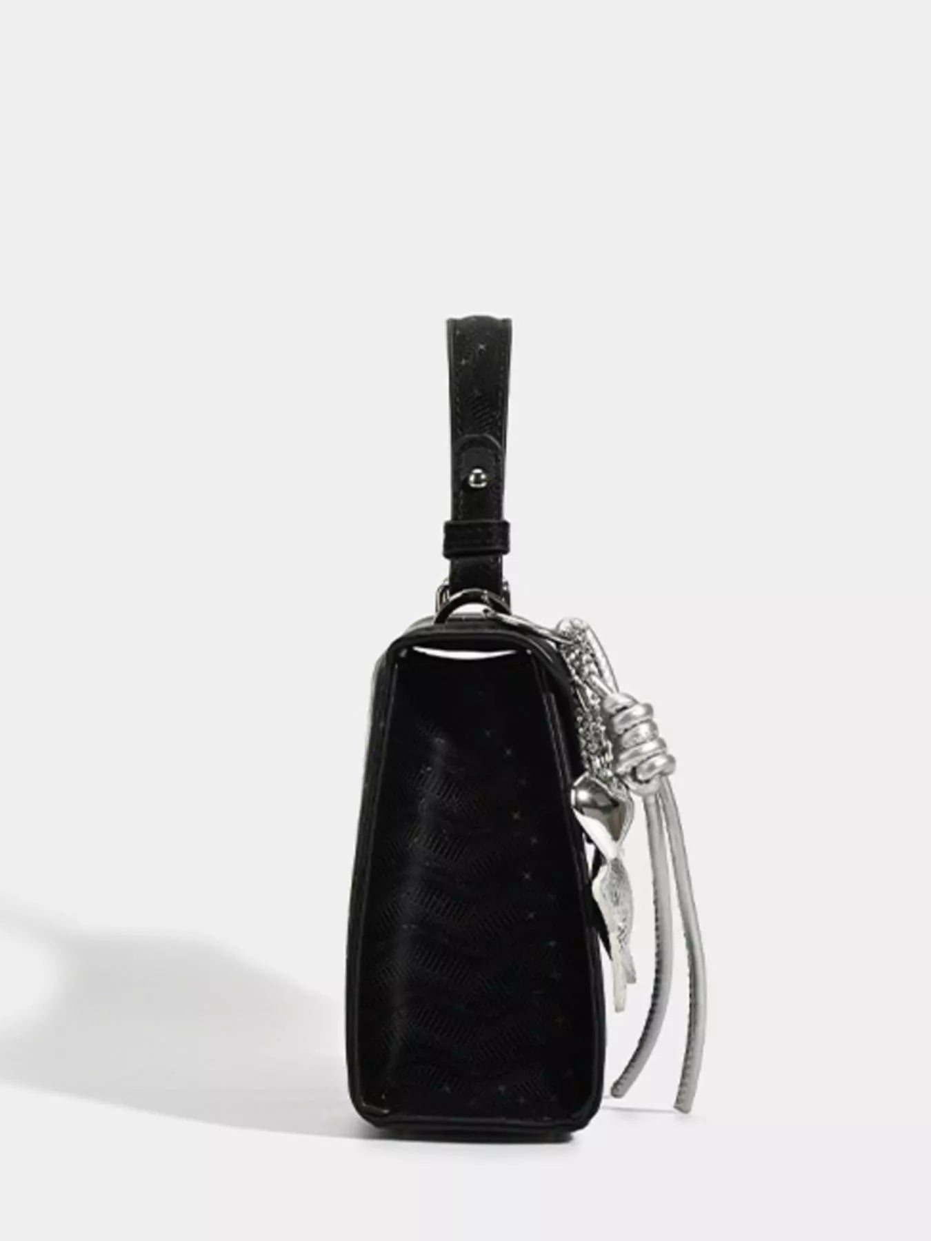 Black textured mini handbag with silver chain strap and tassel detail, stylish fashion accessory